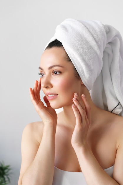 a natural woman with good skin holds her cheeks and looks in the mirror. spa, cosmetology, beauty