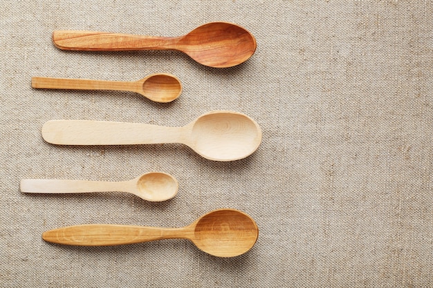 Natural wood spoons in a row on burlap fabric. Natural natural materials. Caring for the environment