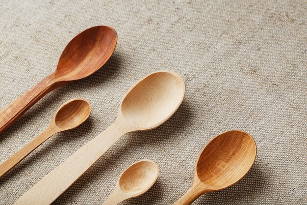 Natural wood spoons in a row on burlap fabric. Natural natural materials.