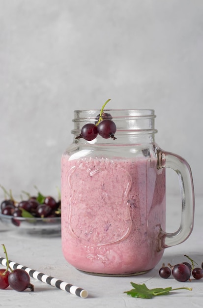 Natural yogurt and black currant smoothie in glass jar on light gray background