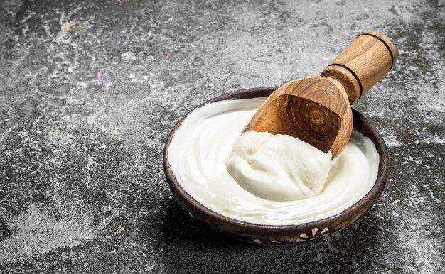 Natural yogurt in a bowl. On a rustic background.