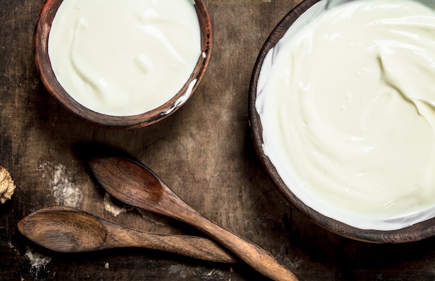 Natural yogurt in a bowl with a spoon. On a wooden table.