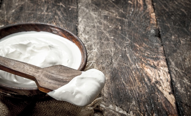 Yogurt naturale in una ciotola. su uno sfondo di legno.