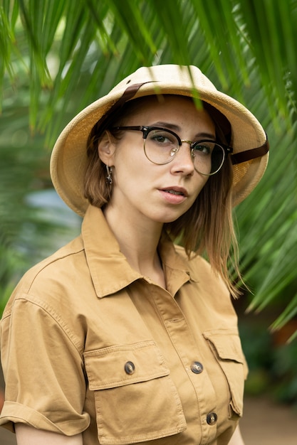 Naturalist in khaki clothes in rainforest surrounded by palms