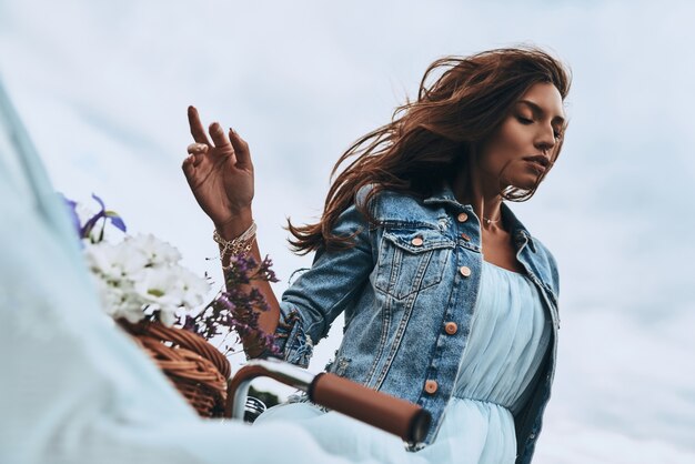 Naturally beautiful. Attractive young woman in dress keeping eyes closed while standing next to her old fashioned bicycle