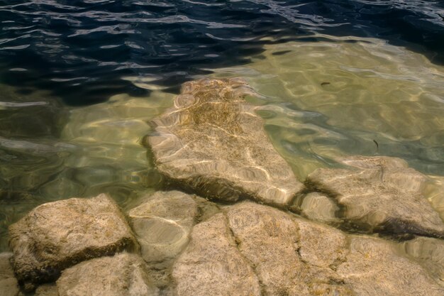 Nature background with big granite stones in transparent water on bottom