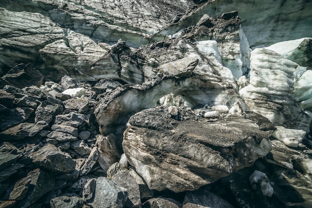 Nature background with icefall near glacier wall with cracks and scratches. Natural backdrop with icy wall and blocks of ice. Beautiful landscape with shiny glacial wall and ice blocks in sunlight.