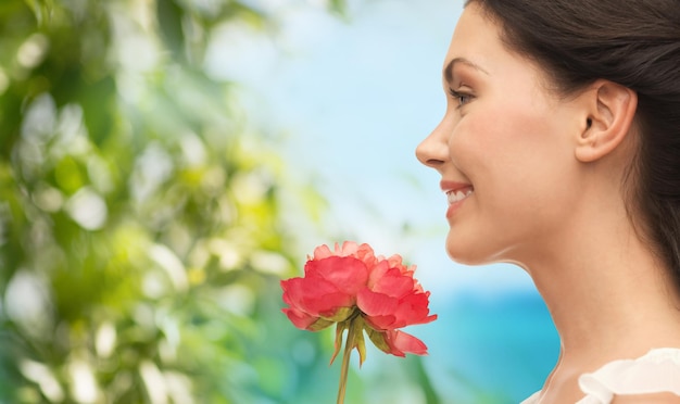 концепция природы и красоты - улыбающаяся женщина, нюхающая цветок - улыбающаяся женщина, нюхающая цветок