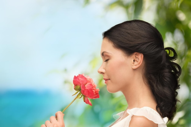 nature and beauty concept - smiling woman smelling flower with eyes closed