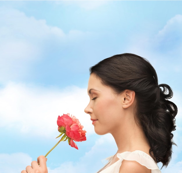 nature and beauty concept - smiling woman smelling flower with eyes closed