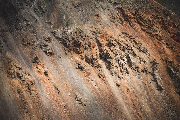 Foto grande bello primo piano roccioso della superficie della montagna della natura. sullo sfondo naturale del gigantesco fianco di montagna scosceso con torrente masso. piano strutturato di massiccio muro montuoso. combe pendii rocciosi.