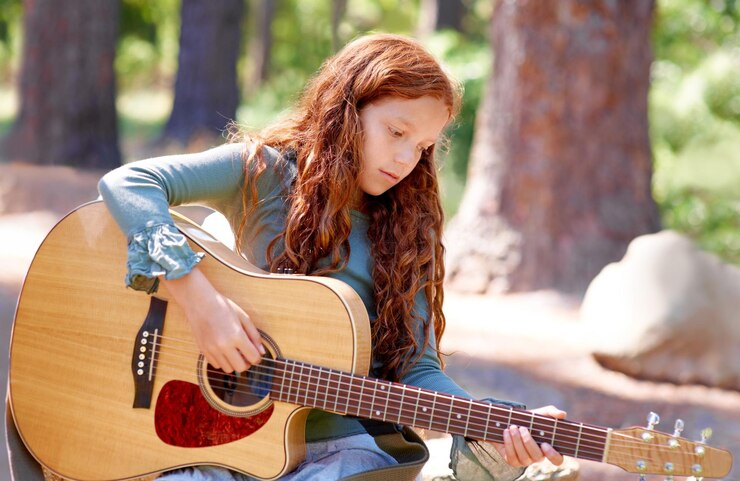 Photo nature camp and girl child with guitar for entertainment talent or music in woods or forest playing musician and kid with acoustic string instrument outdoor in park or field on weekend trip