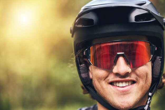 自然のサイクリングとヘルメットの肖像画と冒険のクローズ アップのためのゴーグルと興奮した顔を持つ男頭保護モックアップとスポーツ活動の準備ができて笑顔で幸せで若いアスリート男性