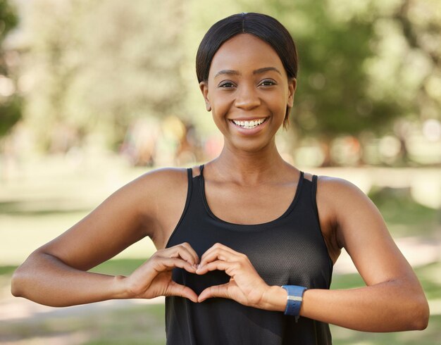 Nature fitness or black woman portrait with heart hand sign loves training exercise outdoor park workout in summer Wellness face or healthy girl with a calm peaceful or happy smile in Nigeria