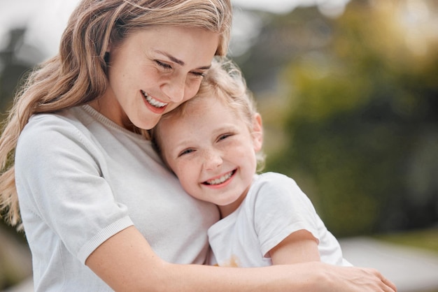 Nature hugging and portrait of child with mother in an outdoor garden bonding together Happy smile and girl kid embracing her young mom from Canada with love and care in the park or field