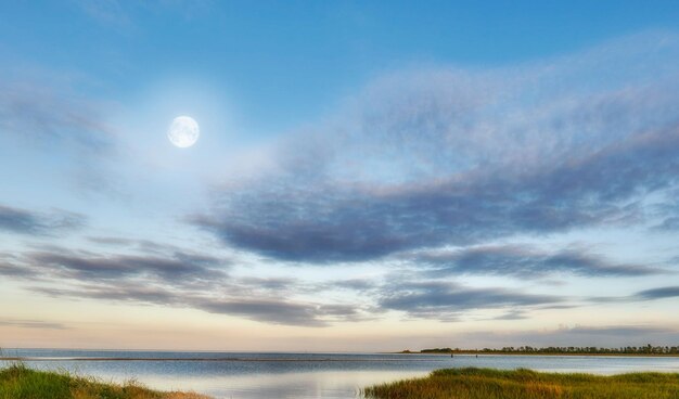 Nature landscape of a cloudy blue sky over the ocean waters Winter sunrise views on empty calm beach at low tide Beautiful seaside scene of the natural peaceful and stressless outdoors