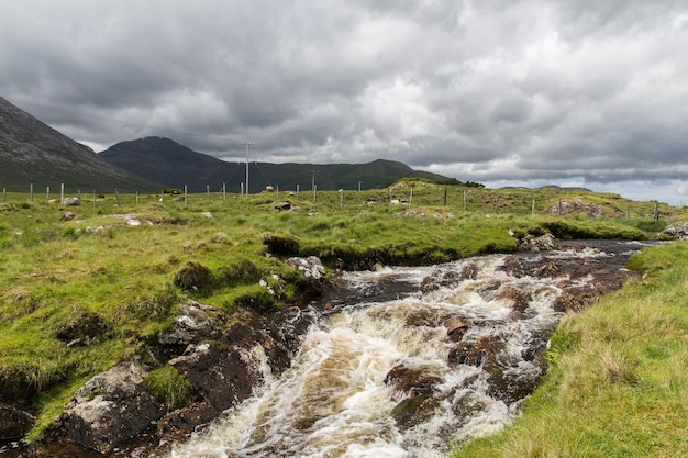 nature and landscape concept - view to river rapids and hills or mountains at connemara in ireland