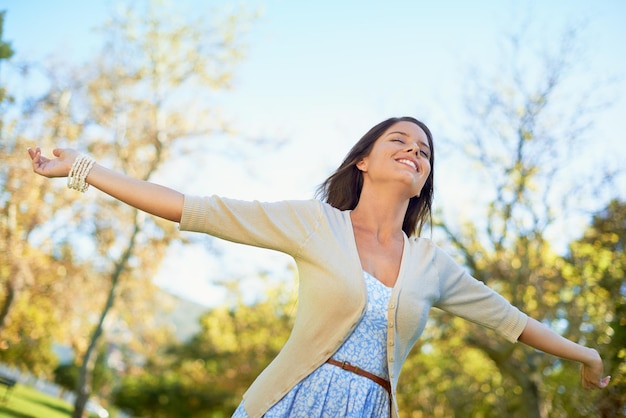 Nature loving Shot of a carefree young woman enjoying a day at the park