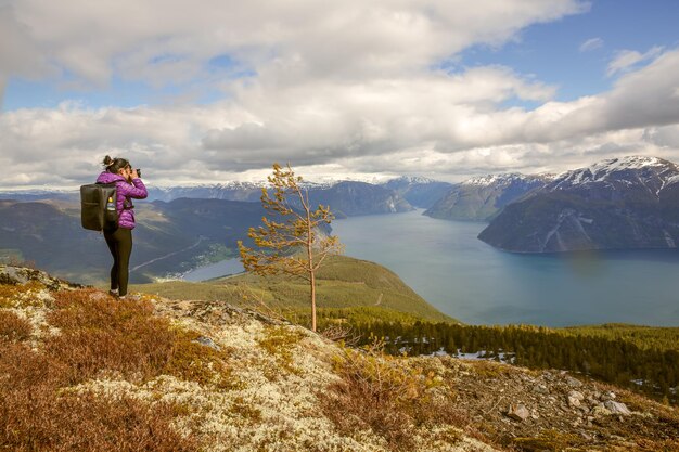 Nature photographer tourist with camera shoots while standing on top of the mountain. Beautiful Nature Norway.