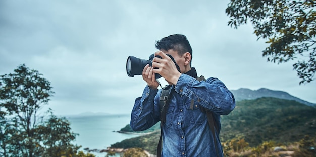 デジタルカメラを持った自然写真家が海や湖の近くで写真撮影をしています。