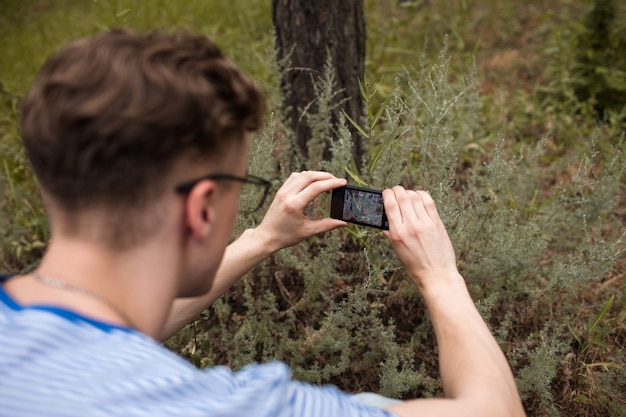 自然写真の趣味。森の中でモバイル写真を撮る男