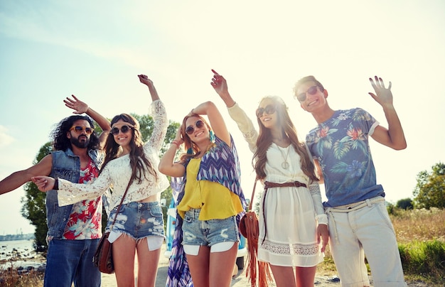 nature, summer, youth culture and people concept - happy young hippie friends dancing outdoors