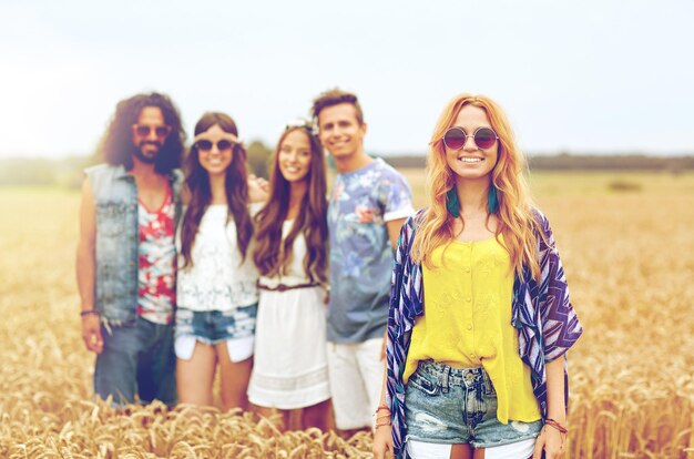 nature, summer, youth culture and people concept - smiling young hippie friends on cereal field