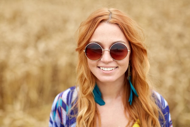 nature, summer, youth culture and people concept - smiling young redhead hippie woman in sunglasses outdoors