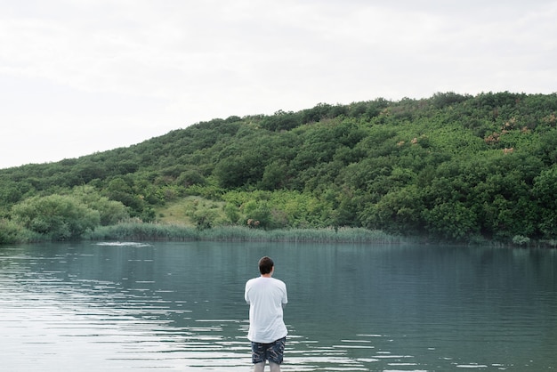 自然と旅行のコンセプト。湖の近くに立っている男の背面図