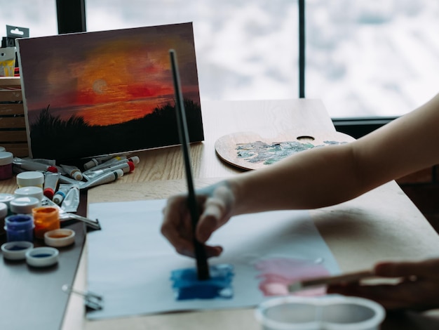 Photo nature view painting cropped shot of talented female artist creating landscape artwork in studio