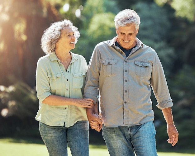 Nature walk and a senior couple holding hands in park laughing and romance in retirement Outdoor garden love and elderly man and happy woman on romantic walking date in a field on summer weekend