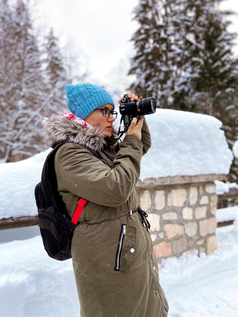 Nature woman landscape photographer in warm clothing taking picture photos. DSLR camera. Winter view