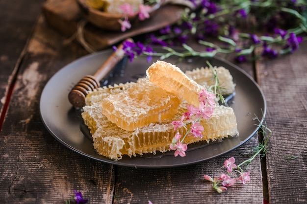 Nature wooden honey dipper and honeycombs on background of wooden