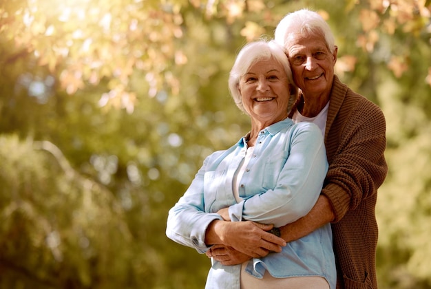 Natuur knuffel portret en senior paar met mockup omarmen buiten in een park samen tijdens pensionering Gelukkig romantiek en liefde met een volwassen man en vrouw knuffelen in een tuin met planten of bomen