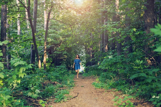 Natuur, mensen en lifestyle concept - mooie jonge vrouw in jurk die in het zomerbos rent