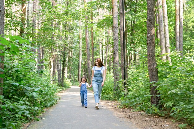 Natuur, moederschap en kind concept - Gelukkige moeder en dochtertje hebben plezier in groen park.