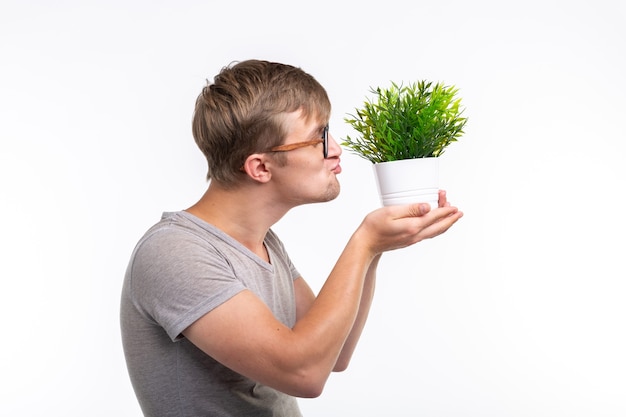 Natuur, plezier, gek rond en nerd concept - Portret van grappige jonge man een plant kussen over de