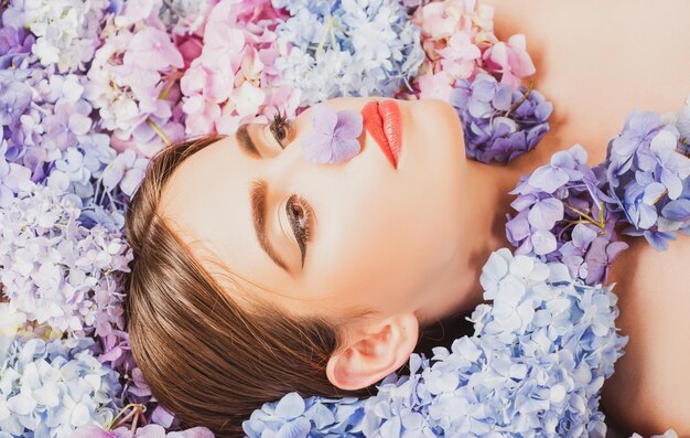 Natuur schoonheid vrouw liggend op bloemen bloesem make-up cosmetica en huidverzorging meisje met hortensia bloemen