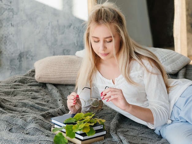 Natuur studie concept. Bioloog hobby. Portret van vrouwelijke wetenschapper die rust op bed met boeken heeft.