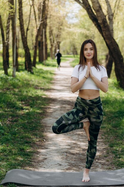 Natuur voor het leven Outdoor lifestyle sportieve gezonde vrouw ontspannen en beoefenen van yoga pose onder de boom in het openbare natuurpark bij zonneschijn tijd