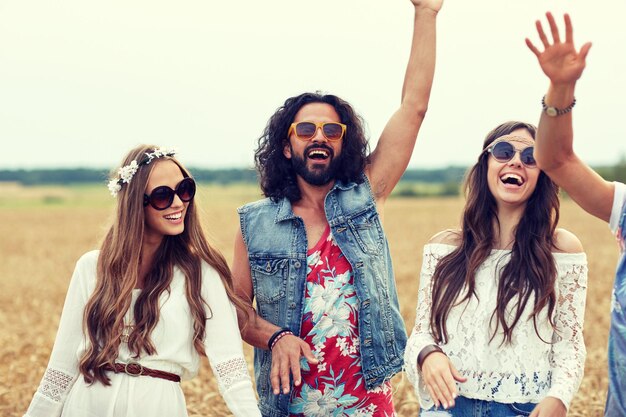 natuur, zomer, jeugdcultuur en mensenconcept - gelukkige jonge hippievrienden dansen op graanveld