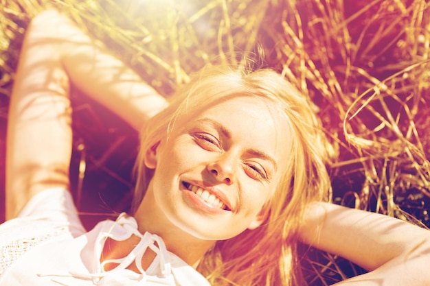 Foto natuur, zomervakantie, vakantie en mensenconcept - gelukkige jonge vrouw liggend en genietend van de zon op graanveld