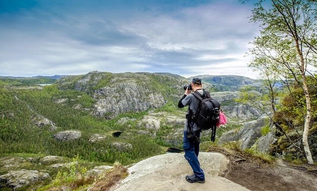 Natuurfotograaf toerist met camera schiet terwijl hij op de top van de berg staat. Prachtige natuur Noorwegen.