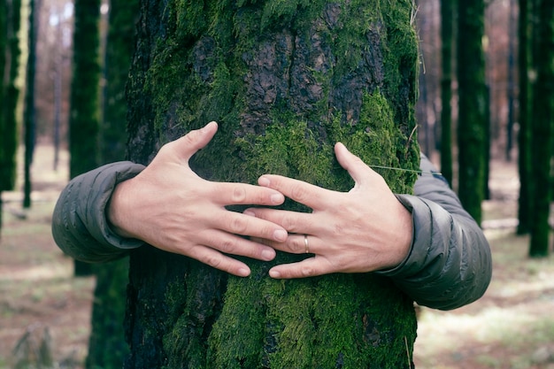 Natuurliefhebber omhelst stamboom met groene muskus in tropisch bos bos Groene natuurlijke achtergrond Concept van mensen houden van de natuur en beschermen tegen ontbossing of vervuiling of klimaatverandering