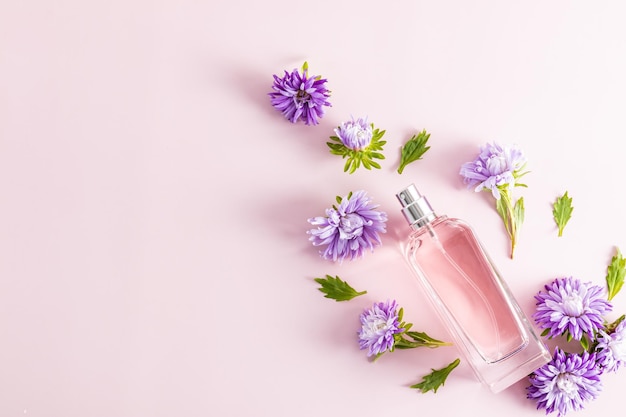 Natuurlijk cosmetisch product in een glazen fles op een roze achtergrond en herfstbloemenpresentatie van parfumruimte voor tekst