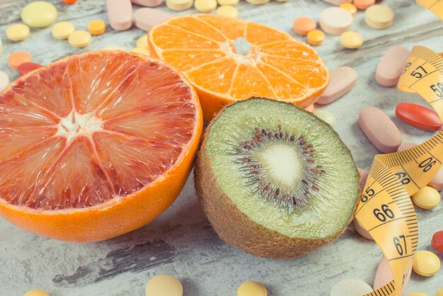 Foto natuurlijk fruit en medische pillen keuze tussen het eten van fruit en het nemen van supplementen om de immuniteit te versterken