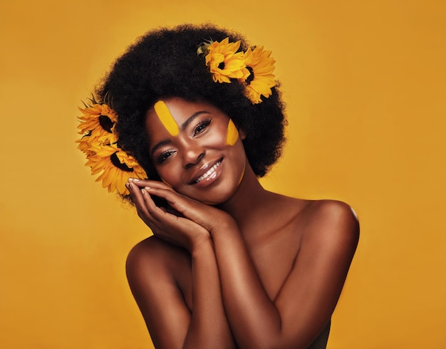 Natuurlijk haar en zonnebloem met portret van zwarte vrouw in studio voor creatieve schoonheid of lente Make-up cosmetica en bloemen met gezicht van model op gele achtergrond voor kunst zelfliefde of zelfvertrouwen