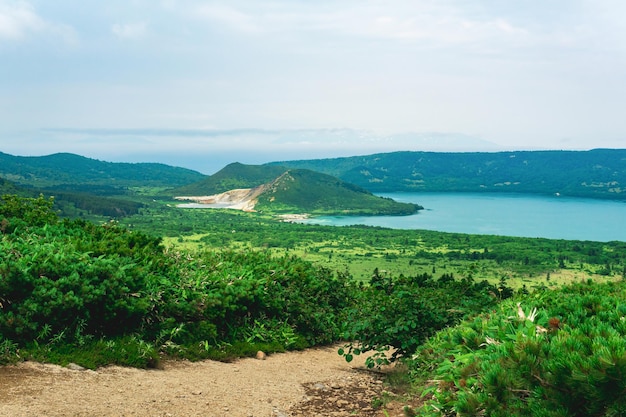 Natuurlijk landschap van Kunashir-eilandmening van de Golovnin-vulkaancaldera met hete meren en een weg door het struikgewas van sasa en dwergdennen op een voorgrond