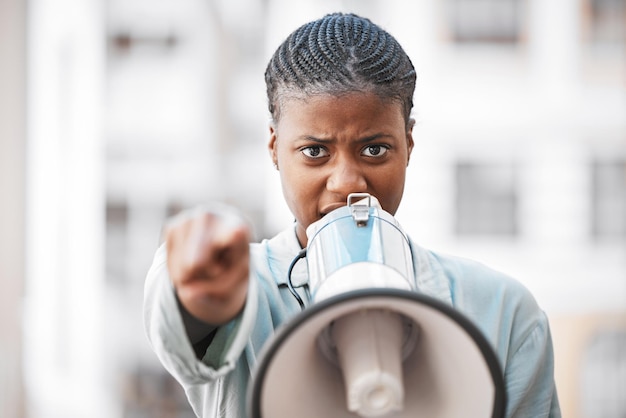 Natuurlijk maak ik me geen zorgen over intimiderende mannen Shot van een jonge vrouw die in een luidspreker schreeuwt terwijl ze protesteert in de stad