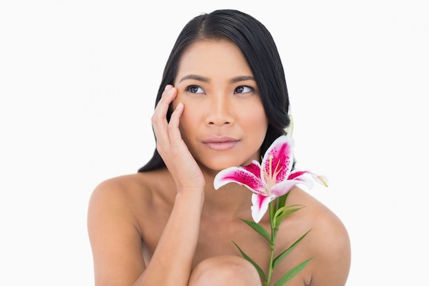 Natuurlijk model poseren met lelie en aanraken van haar gezicht